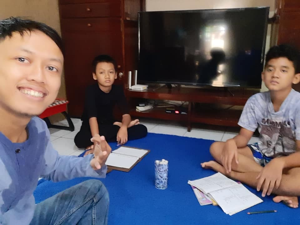 Dua siswa SD belajar bahasa Inggris bersama tutor di ruang keluarga