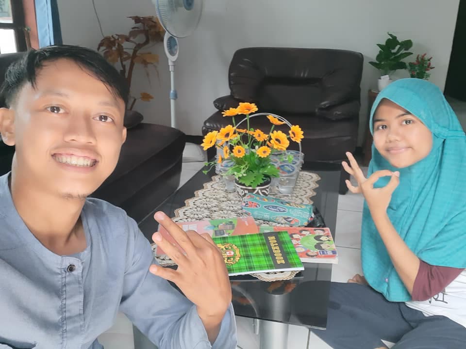 Siswi belajar bahasa Inggris dengan buku catatan bersama tutor