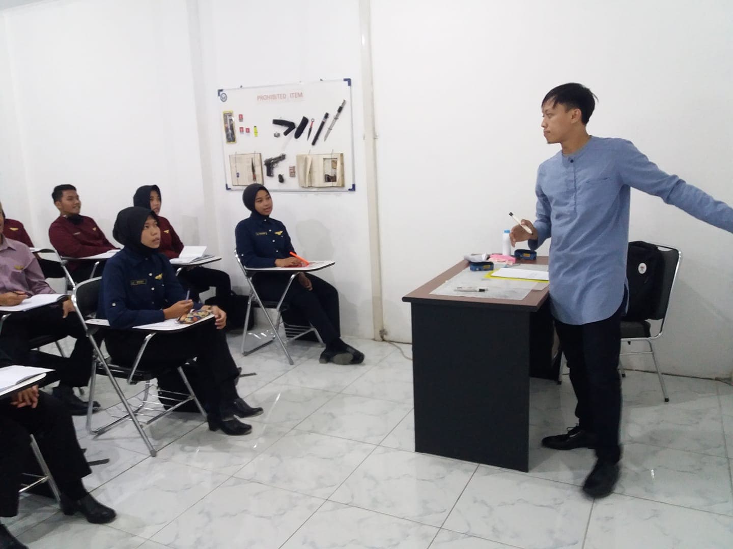 Mr. Dream memandu pelatihan bahasa Inggris di depan peserta dewasa berseragam di ruang kelas