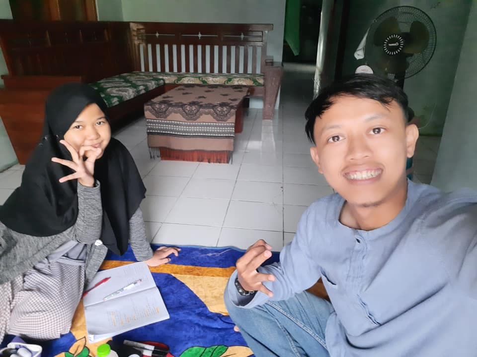 Mr. Dream dan siswi berkerudung hitam belajar kosakata bahasa Inggris sambil duduk lesehan di ruang keluarga